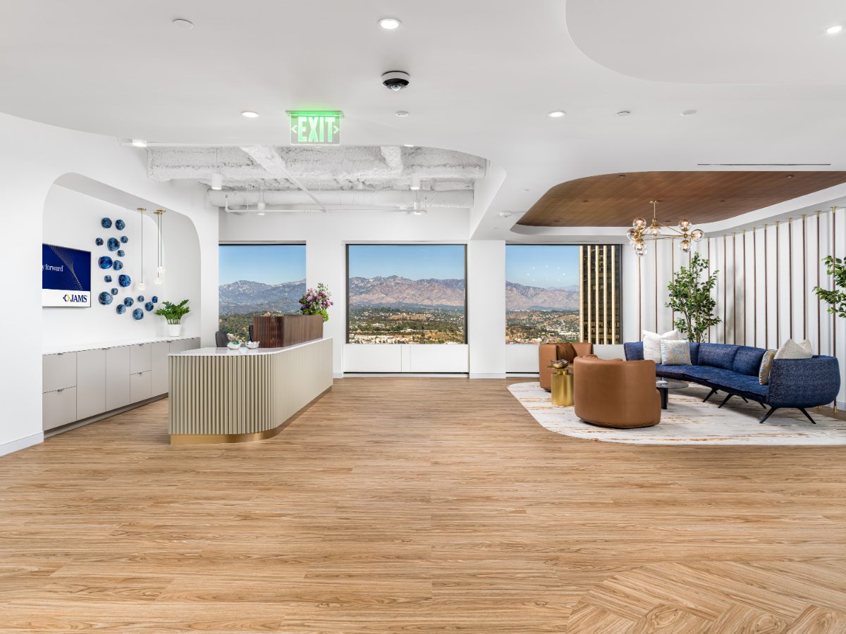 JAMS Los Angeles reception — fluted desk, blue chesterfield lounge, globe-cluster chandelier, and picture windows onto the San Gabriel Mountains.