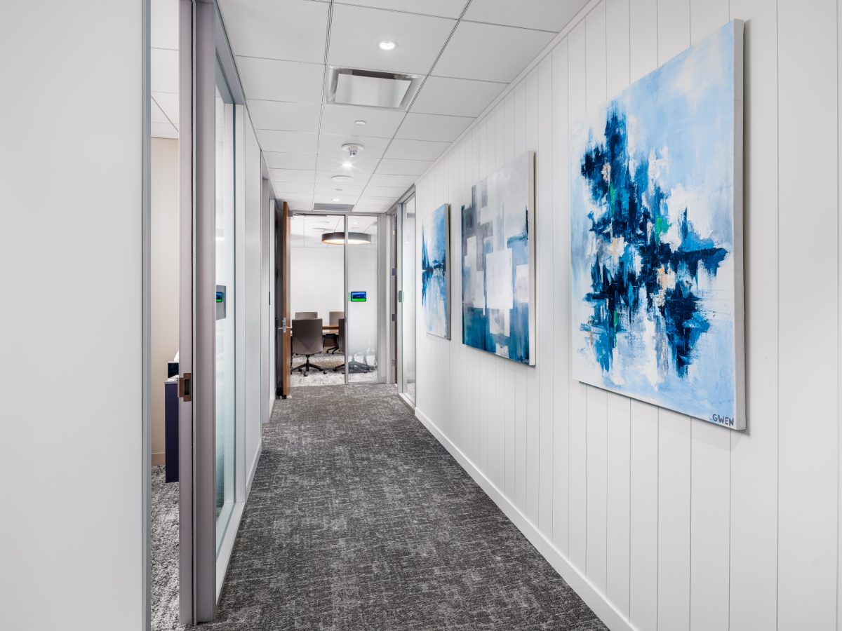 JAMS Atlanta hallway at Promenade Tower — three abstract blue paintings by local artist Gwen on a white shiplap wall, glass meeting room opposite.