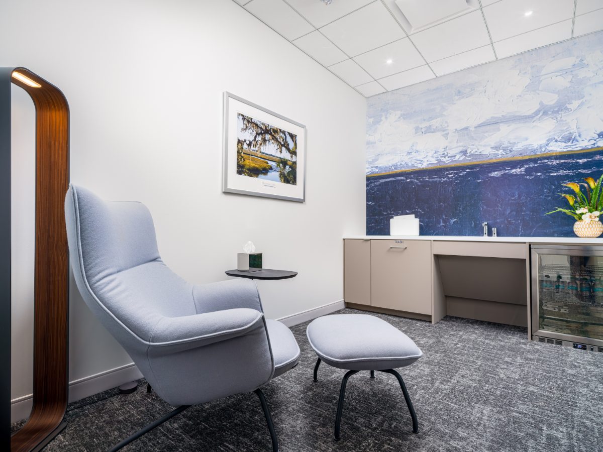 JAMS Atlanta wellness center at Promenade Tower — lavender lounge chair with ottoman, sculptural lamp, kitchenette, blue abstract and Lowcountry landscape art.