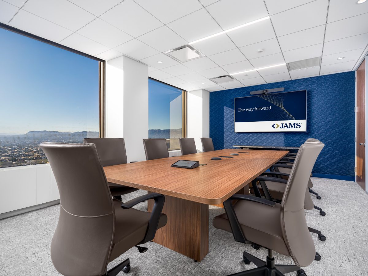 JAMS LA Conference Room 27 — walnut table, charcoal leather chairs, navy seigaiha-pattern wall with JAMS display, corner windows onto the Verdugo foothills.