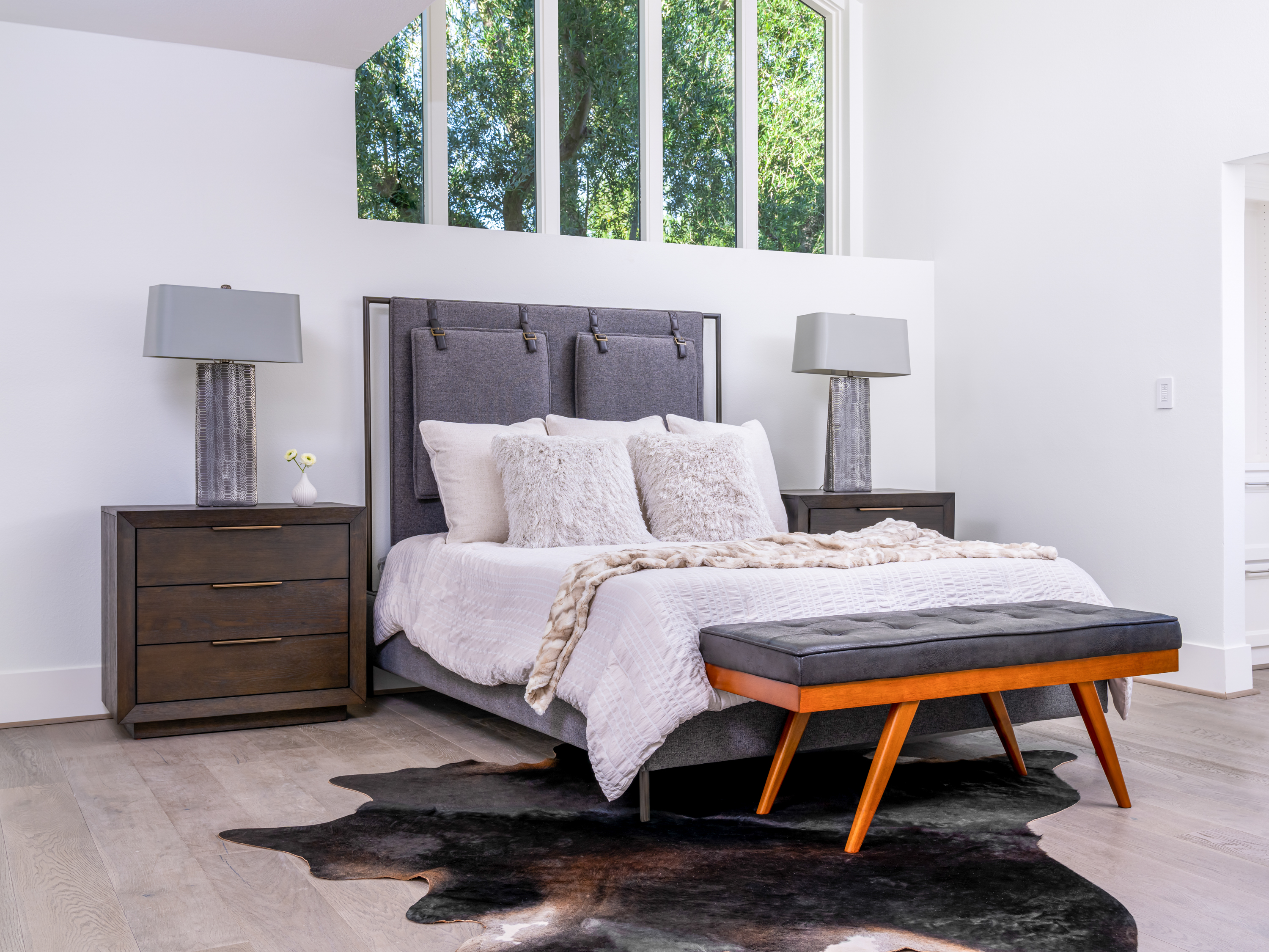Bedroom at a Stately open contemporary home in Las Vegas (2327 AD) — vaulted ceiling, central fireplace, faceted metallic coffee table, blue accent art.