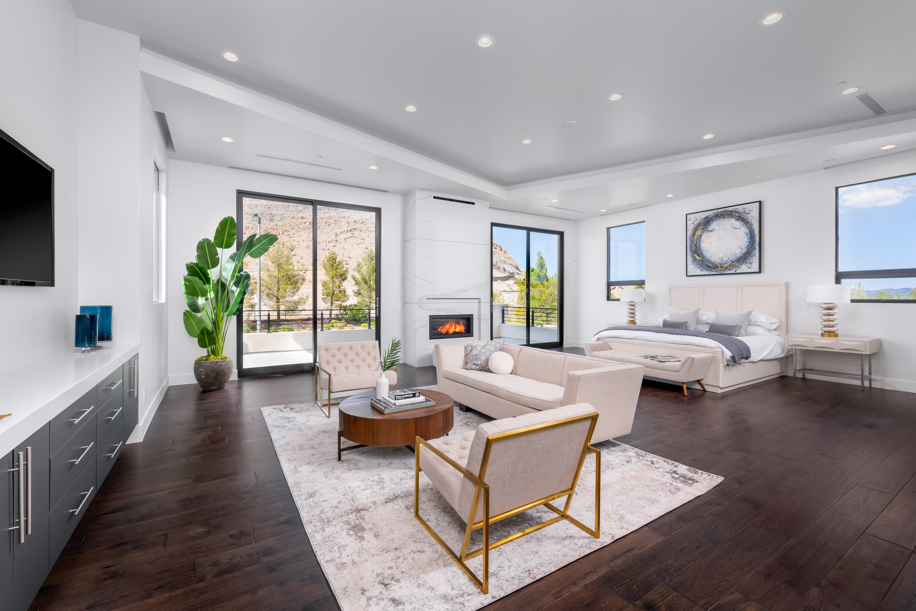 Master Bedroom at a Stately modern desert resort home in Las Vegas (38 RA) — marble fireplace surround, walnut accent stool, abstract art, palm view.