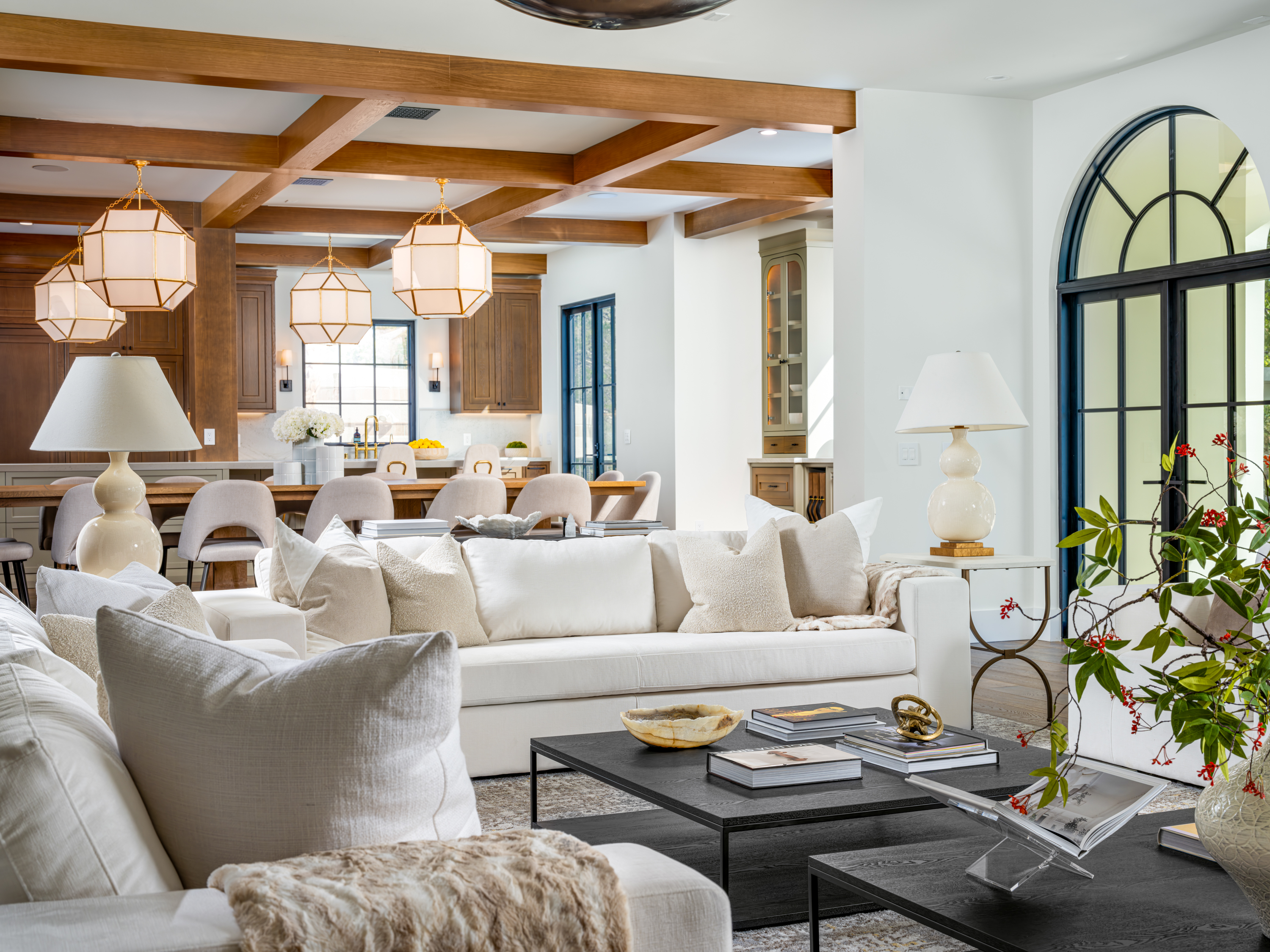 Living Room at a Stately Mediterranean revival home in Las Vegas (8833 GL) — exposed wood ceiling beams, brass pendant lanterns, cream sofas, dark coffee tables.
