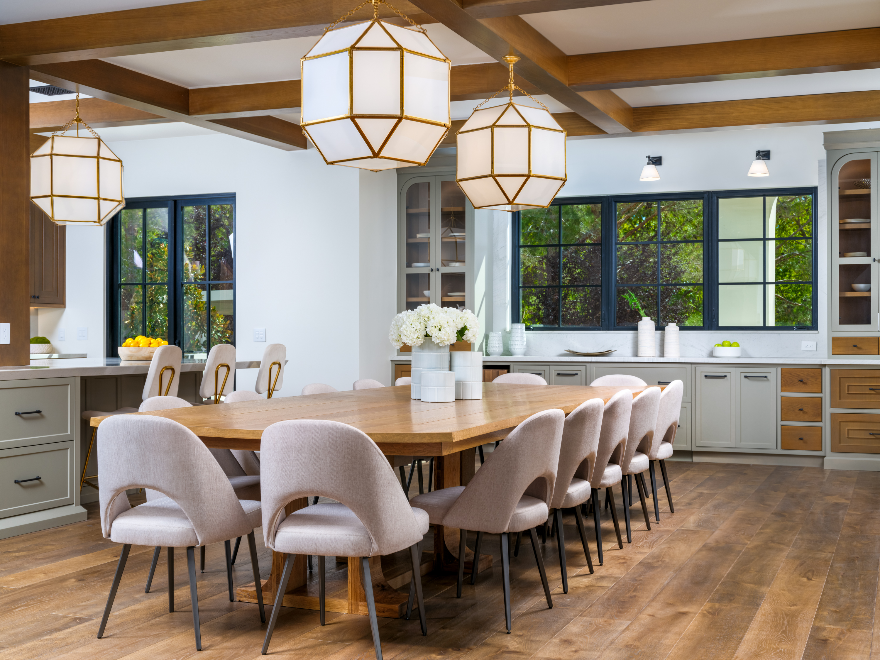 Dining Room at a Stately Mediterranean revival home in Las Vegas (8833 GL) — exposed wood ceiling beams, brass pendant lanterns, cream sofas, dark coffee tables.