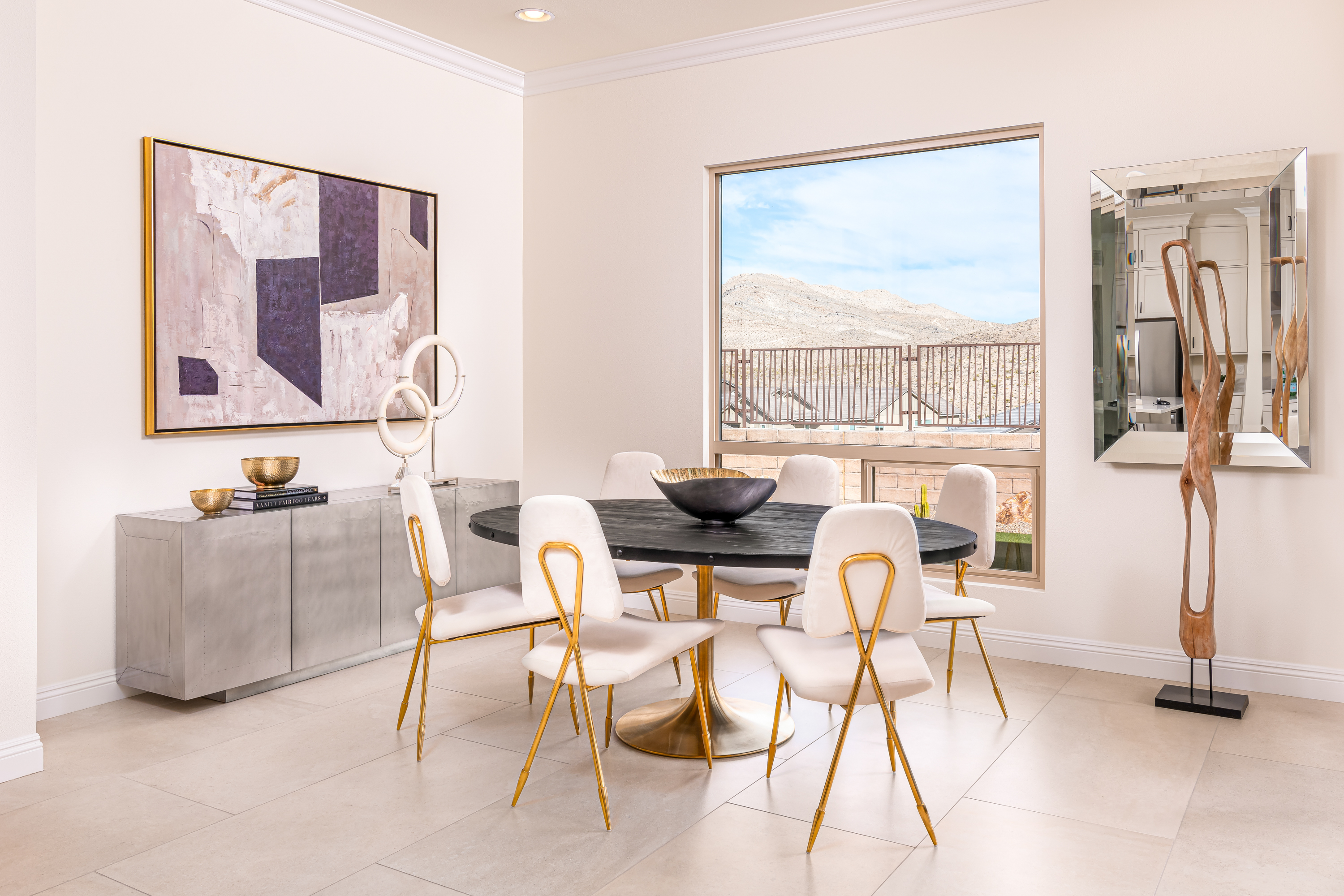 Dining Room at a Stately glam dining home in Las Vegas (11120 RYD) — black pedestal table on gold base, gold-leg velvet chairs, abstract art, mountain view.