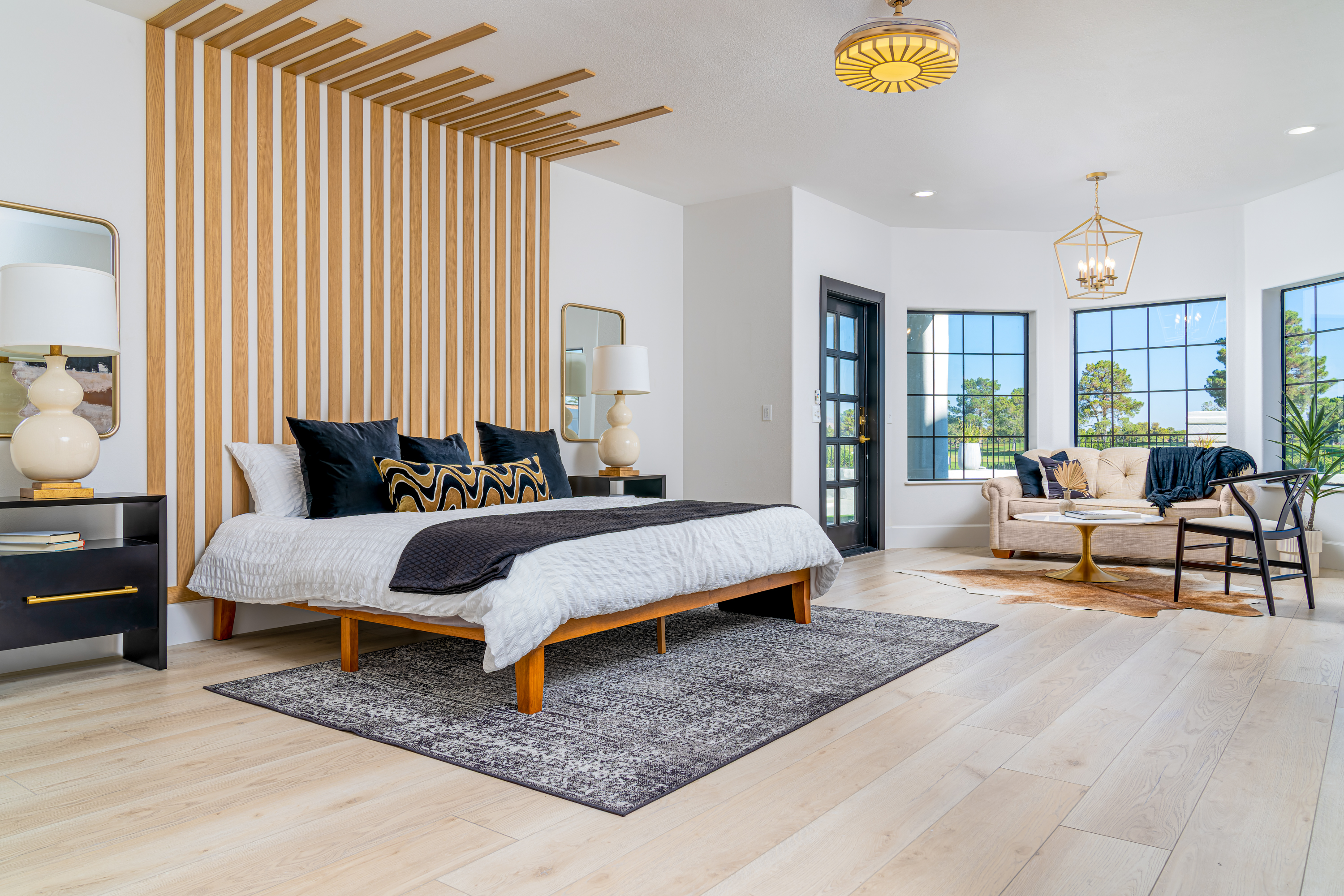 Master Bedroom at a Stately designer bedroom suite home in Las Vegas (15 PL) — vertical wood-slat headboard, platform bed, gold pendant chandelier, ranch view.
