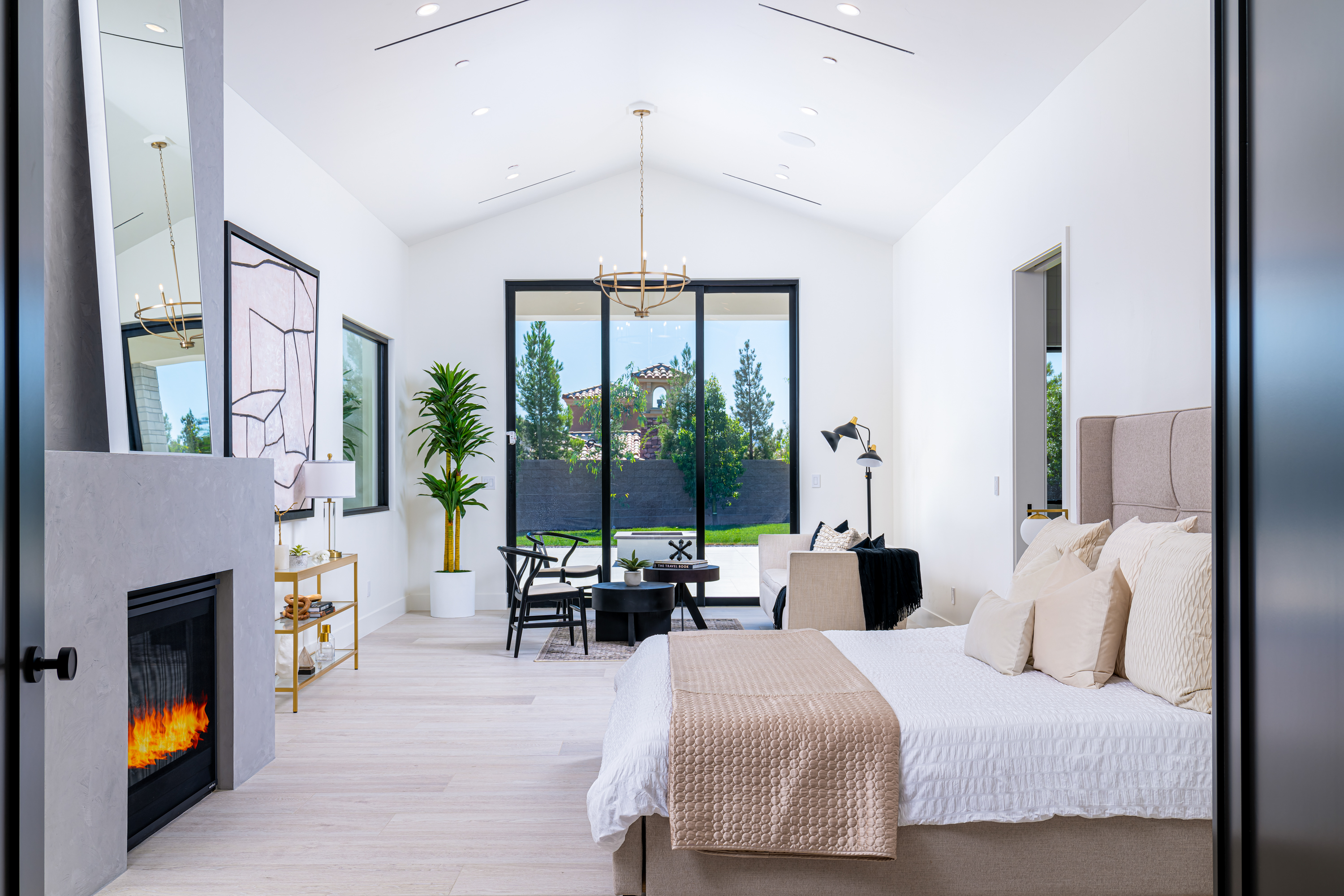 Master Bedroom at a Stately Vegas-luxury indoor-outdoor home in Las Vegas (16 CHC) — wagon-wheel chandelier, tufted ottoman, pleated barrel chairs, pool view.