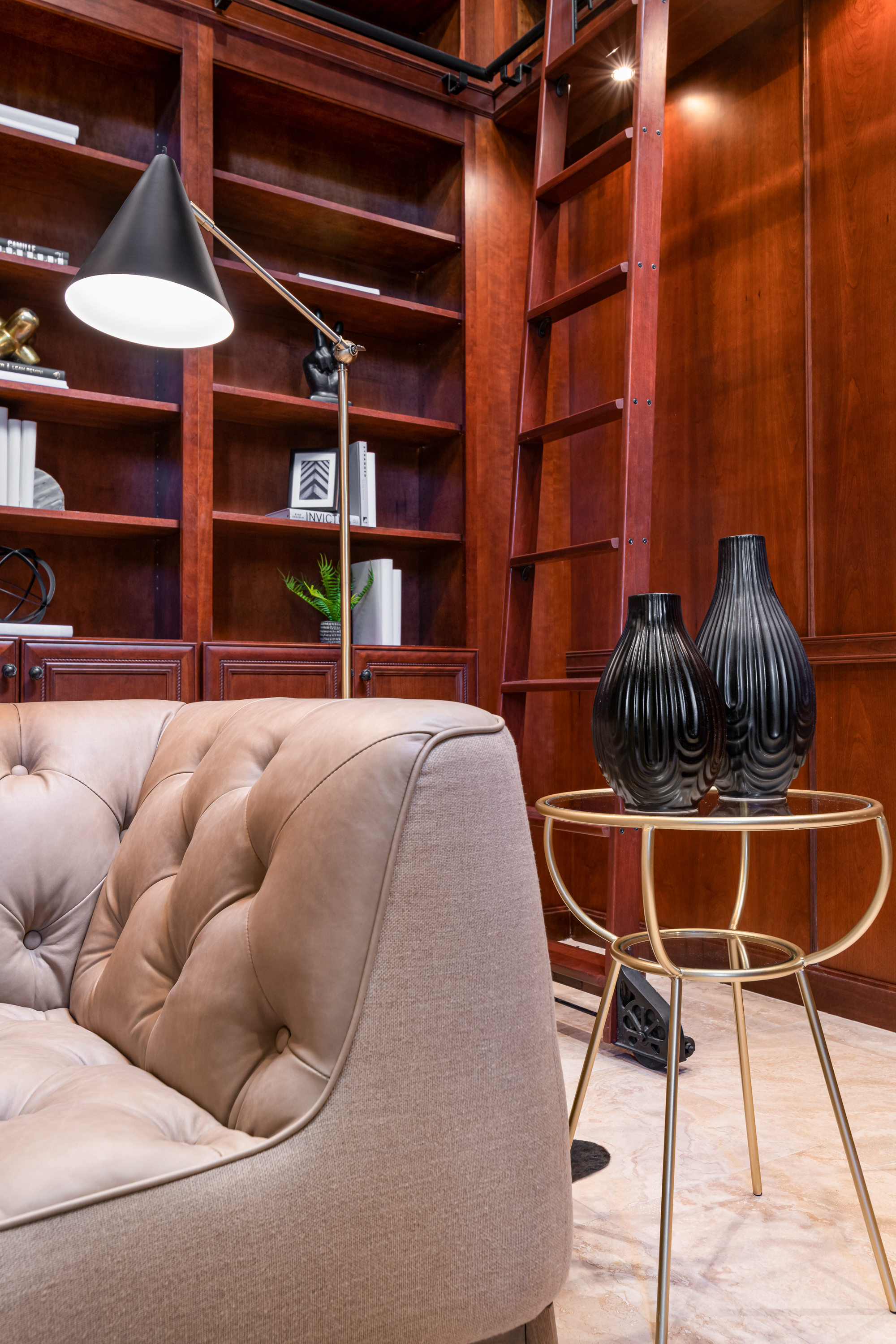Library at a Stately traditional gentleman's library home in Las Vegas (2297 FA) — cherry bookcases, rolling library ladder, tufted cream sofa, antique tripod clock.