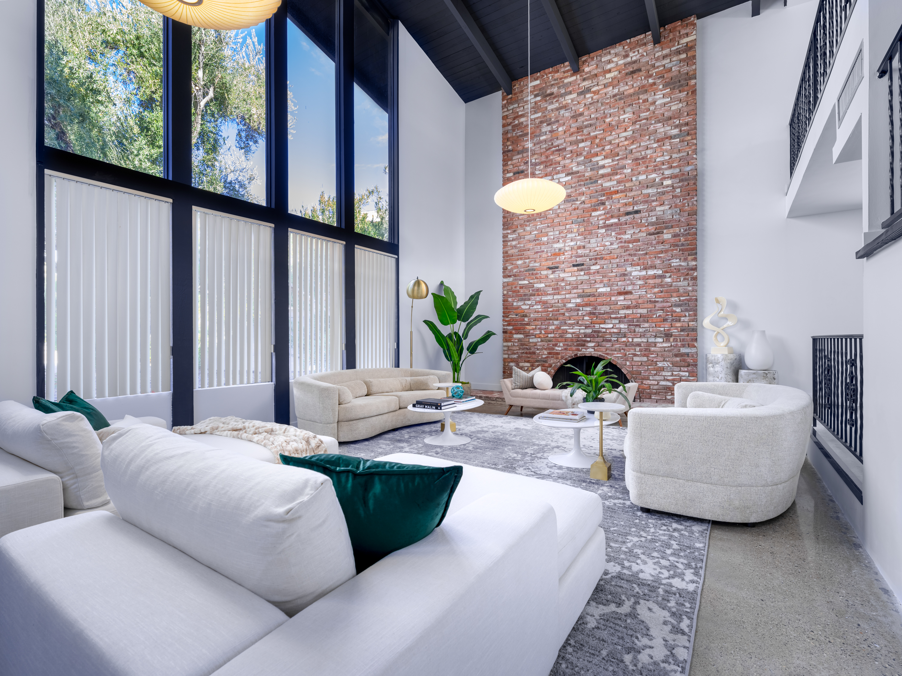 Living Room at a Stately mid-century coastal home in Las Vegas (2305 WW) — vaulted black-beam ceiling, two-story brick chimney, paper lantern, emerald velvet pillows.