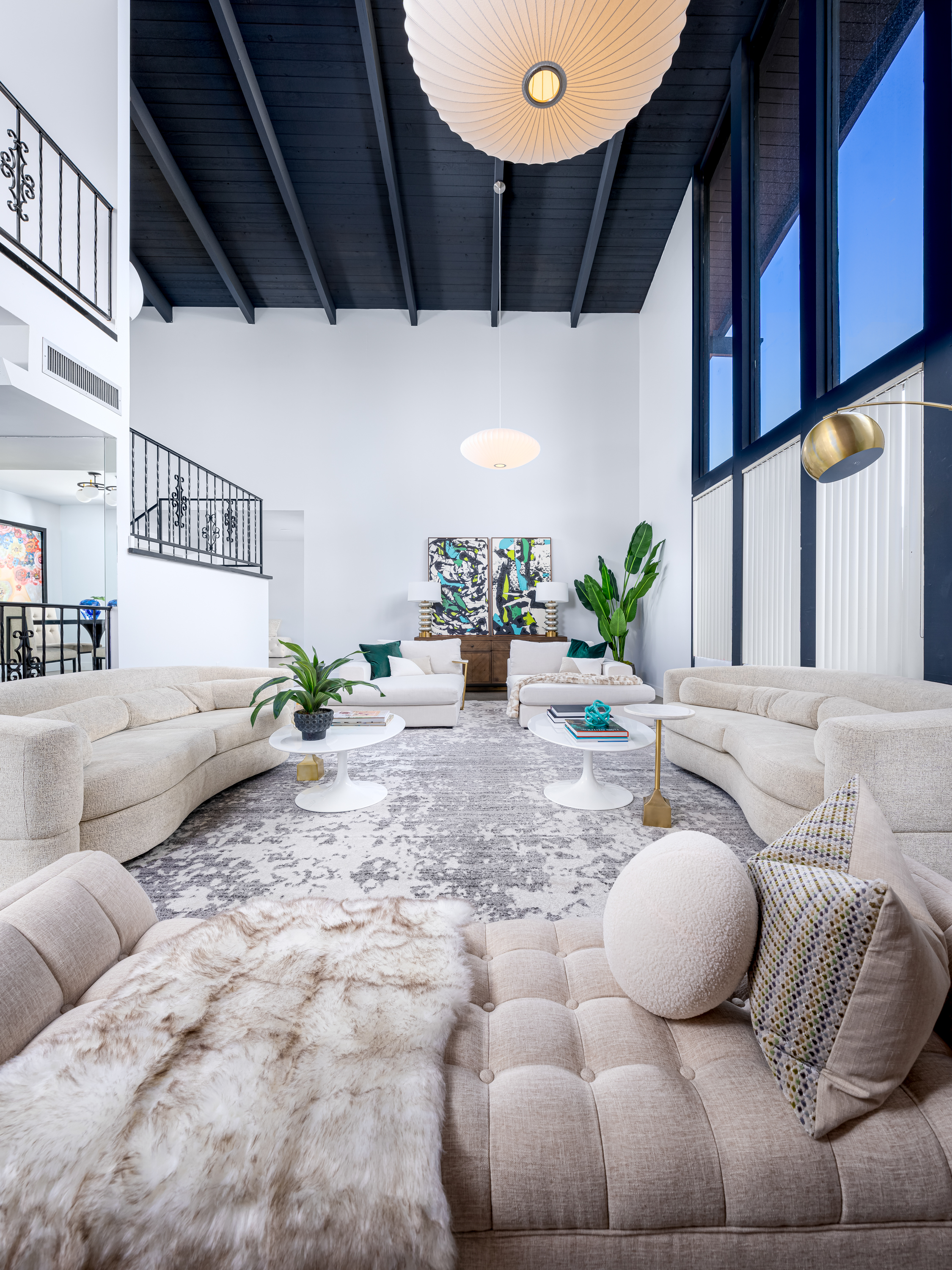 Living Room at a Stately mid-century coastal home in Las Vegas (2305 WW) — vaulted black-beam ceiling, two-story brick chimney, paper lantern, emerald velvet pillows.