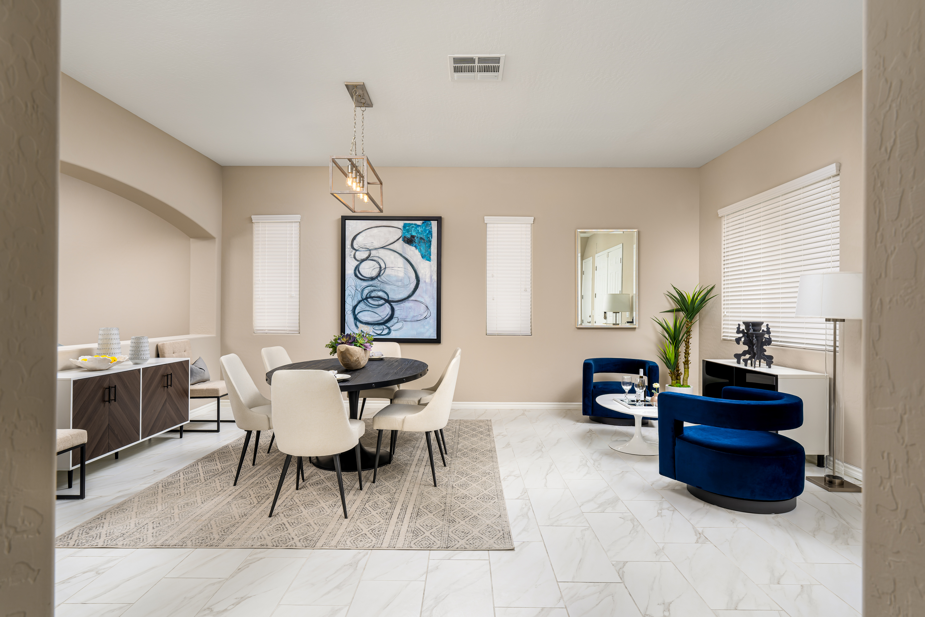 Living Room at a Stately contemporary Moroccan-influenced home in Las Vegas (2818 PSA) — navy velvet chairs, geometric blue-white art, gold accents, marble tile.