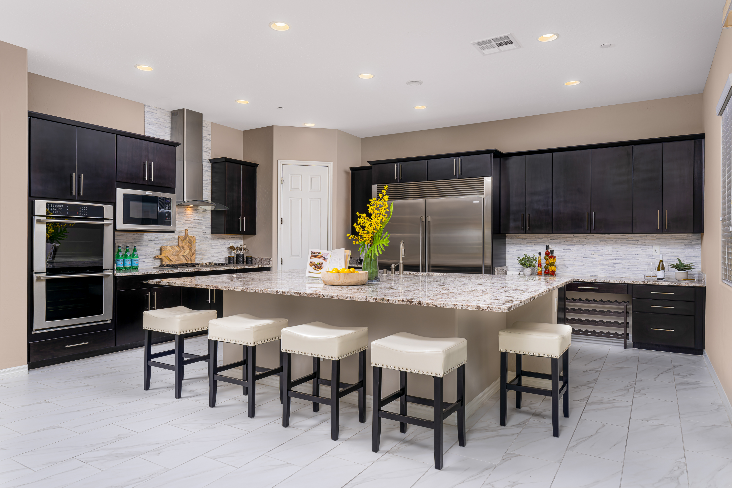 Kitchen at a Stately contemporary Moroccan-influenced home in Las Vegas (2818 PSA) — navy velvet chairs, geometric blue-white art, gold accents, marble tile.