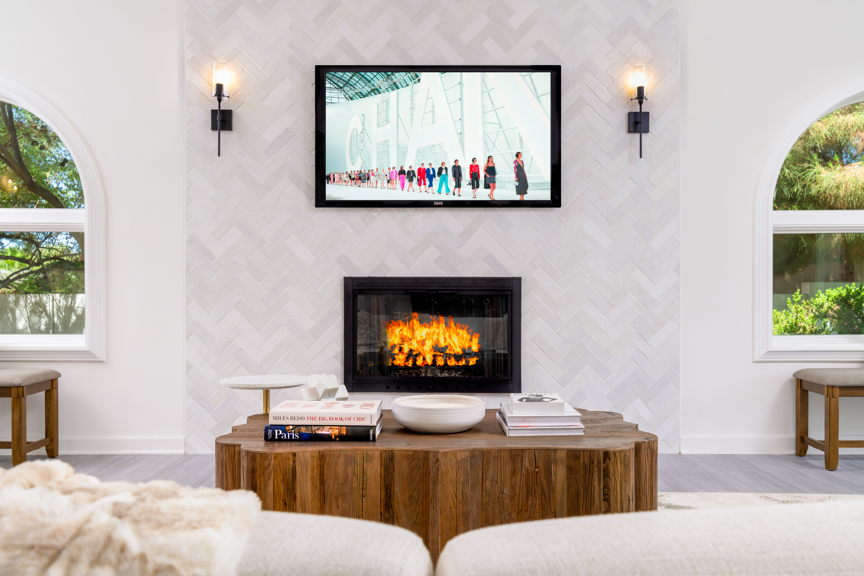 Living Room at a Stately modern luxury fireplace centerpiece home in Las Vegas (3540 ETL) — herringbone tile fireplace, reclaimed wood drum table, bouclé chairs, arched w