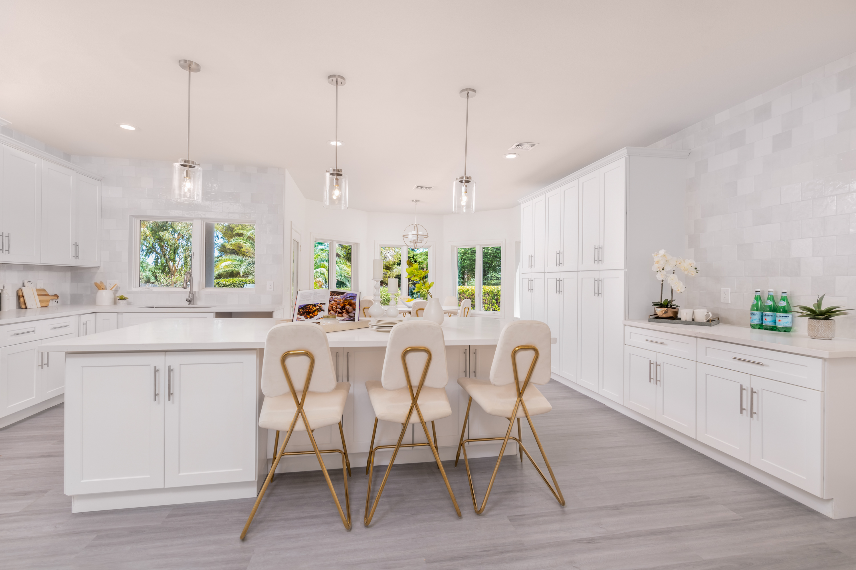 Kitchen at a Stately modern luxury fireplace centerpiece home in Las Vegas (3540 ETL) — herringbone tile fireplace, reclaimed wood drum table, bouclé chairs, arched windo