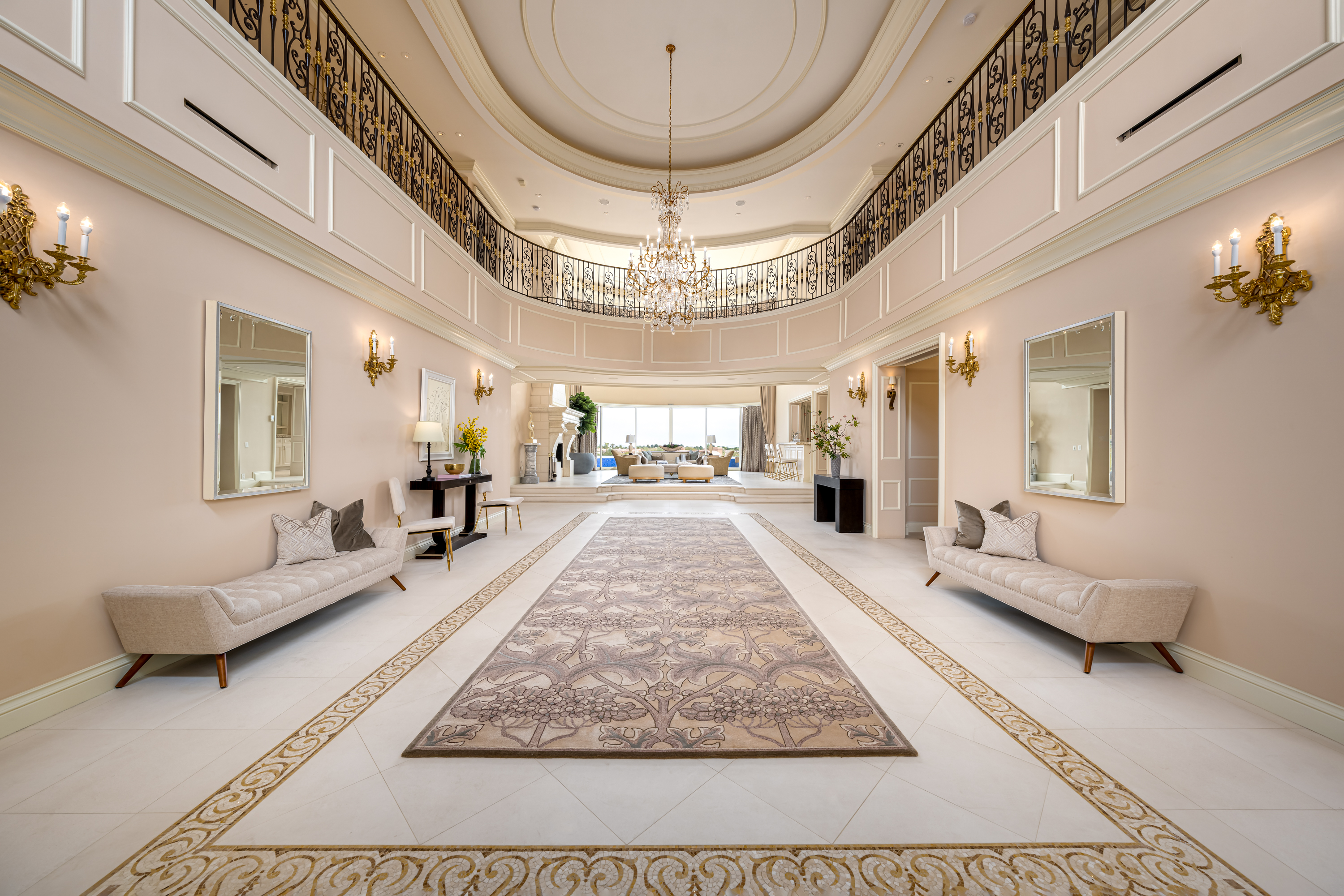 Entrance at a Stately glam estate home in Las Vegas (5114 SHD) — two-story curtains, paired gold-base ottomans, marble fireplace, panoramic view.