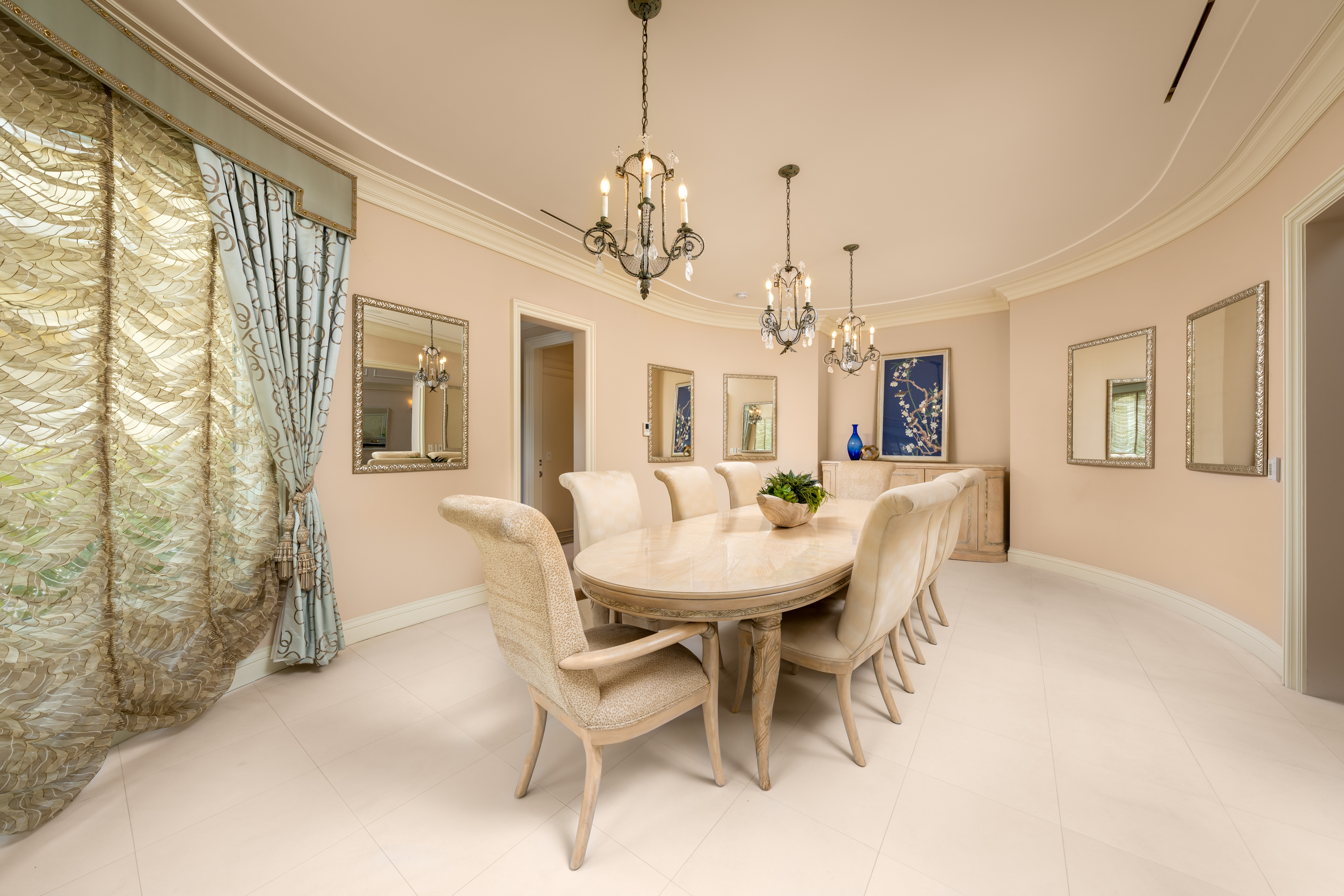 Dining Room at a Stately glam estate home in Las Vegas (5114 SHD) — two-story curtains, paired gold-base ottomans, marble fireplace, panoramic view.