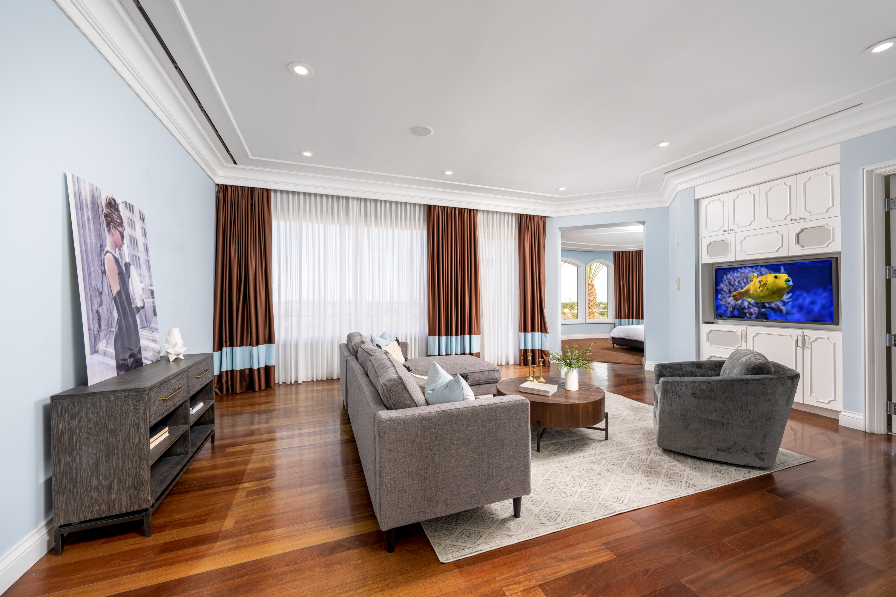 Living Room at a Stately glam estate home in Las Vegas (5114 SHD) — two-story curtains, paired gold-base ottomans, marble fireplace, panoramic view.