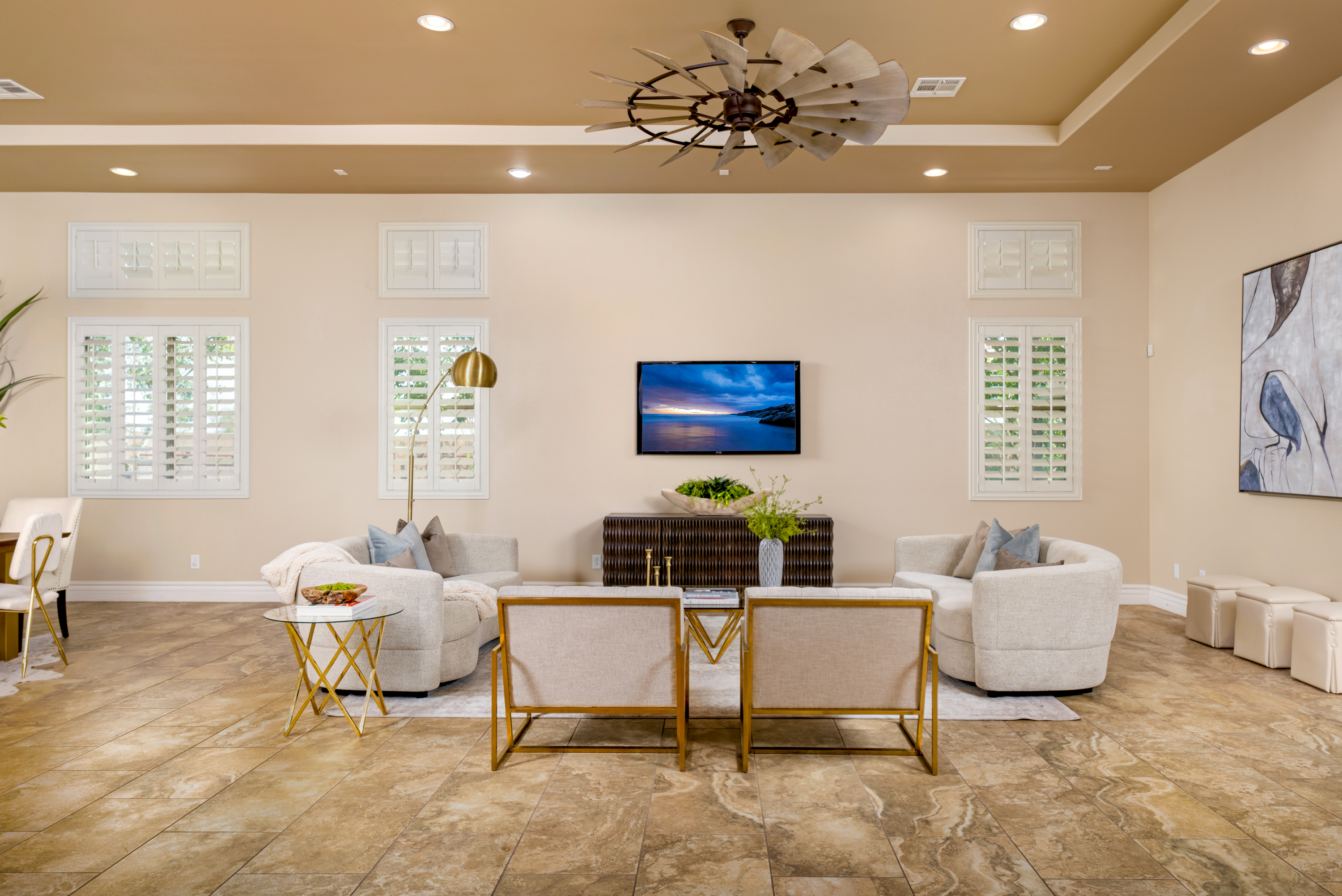 Living Room at a Stately desert ranch traditional home in Las Vegas (7714 FD) — wood-bladed windmill fan, tray ceiling, plantation shutters, swivel chairs.