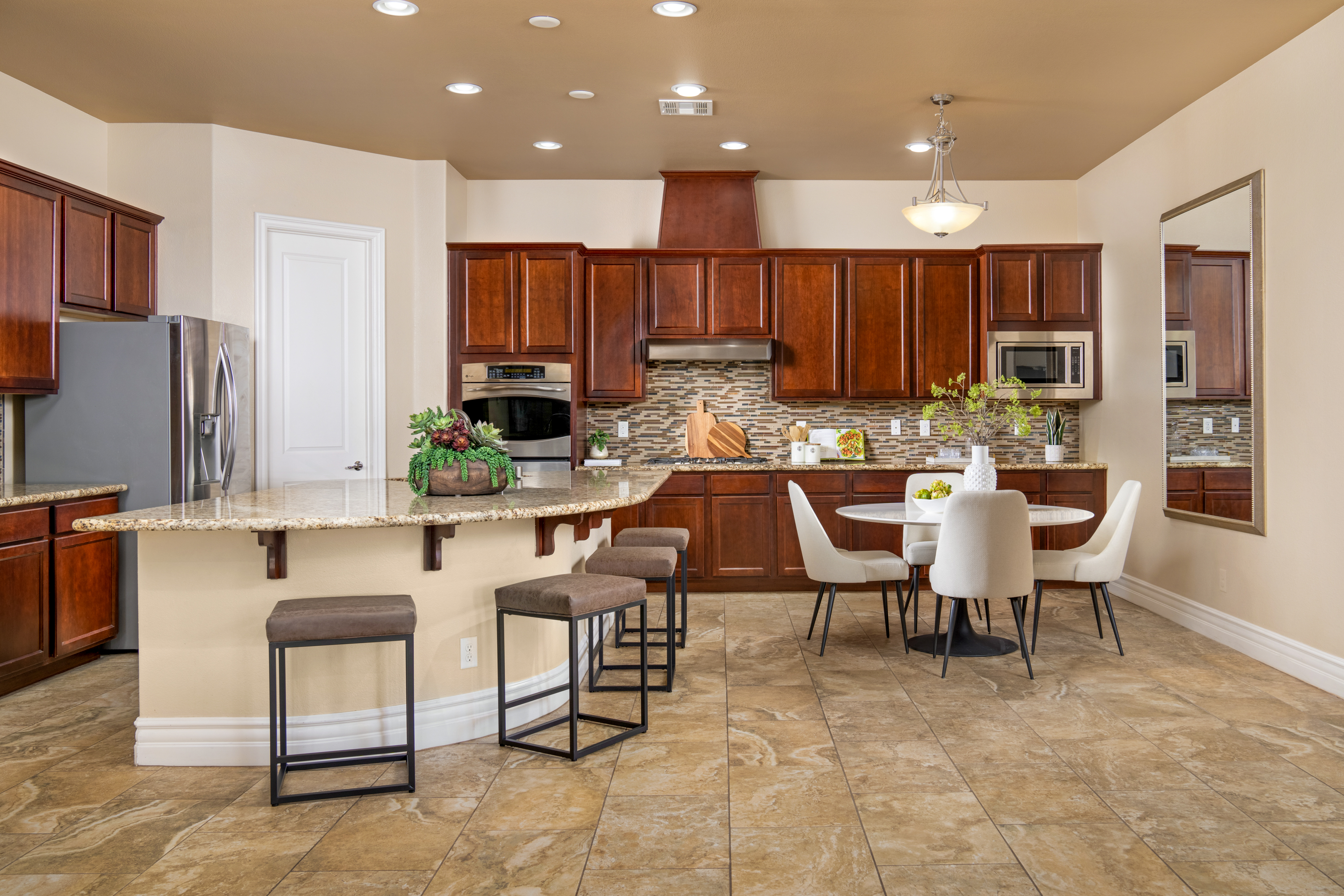Kitchen at a Stately desert ranch traditional home in Las Vegas (7714 FD) — wood-bladed windmill fan, tray ceiling, plantation shutters, swivel chairs.