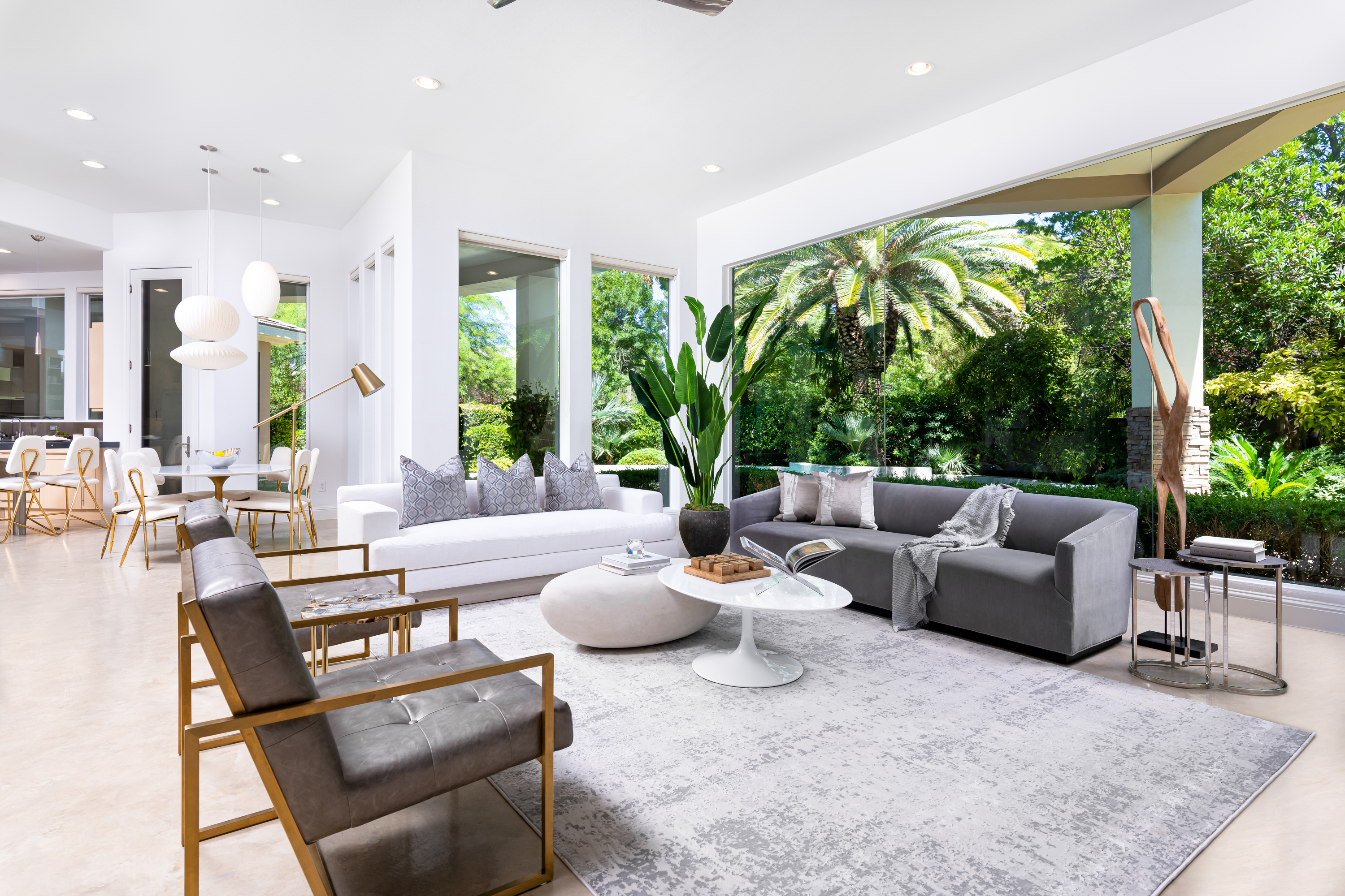 Living Room at a Stately modern luxury w/ wine display home in Las Vegas (9424 TCD) — cylindrical glass wine display, mid-century leather-and-brass chairs, sculptural woo