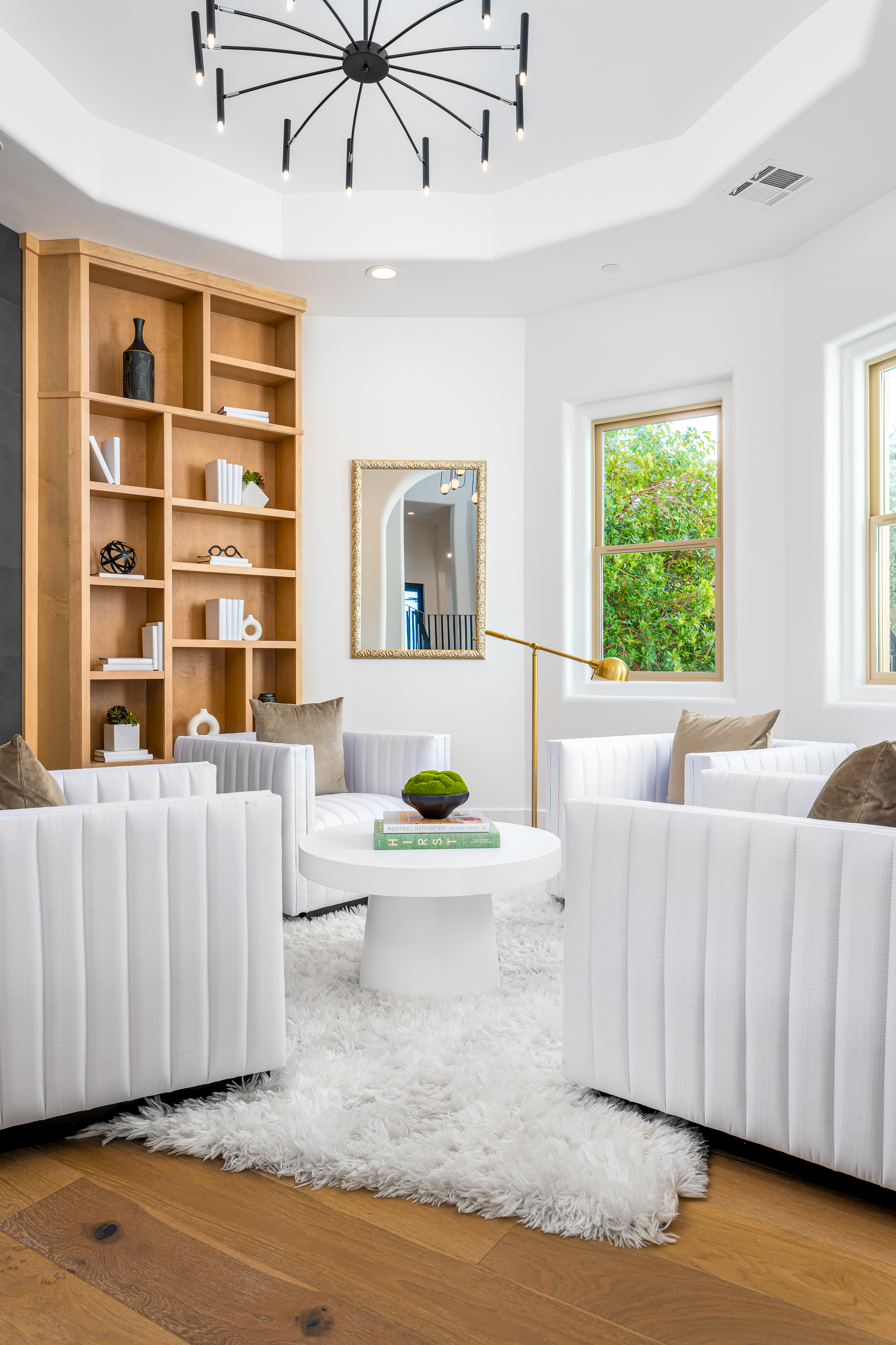 Library at a Stately library sitting room home in Las Vegas (9 YC) — Sputnik chandelier, wood ladder bookcase, channel-tufted swivel chairs, shag rug.
