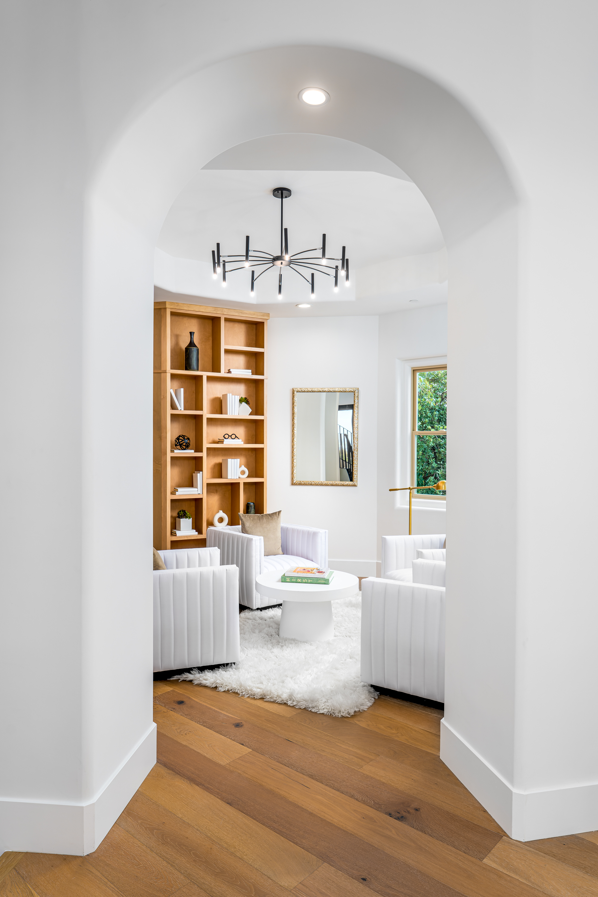 Library at a Stately library sitting room home in Las Vegas (9 YC) — Sputnik chandelier, wood ladder bookcase, channel-tufted swivel chairs, shag rug.