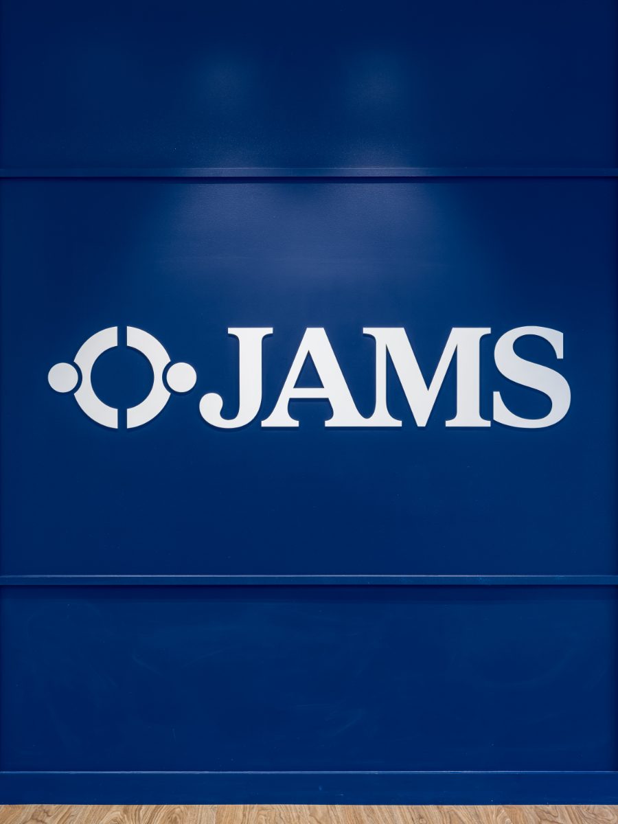 White JAMS wordmark on a deep cobalt blue accent wall above light wood flooring at the JAMS Washington, D.C., Resolution Center.