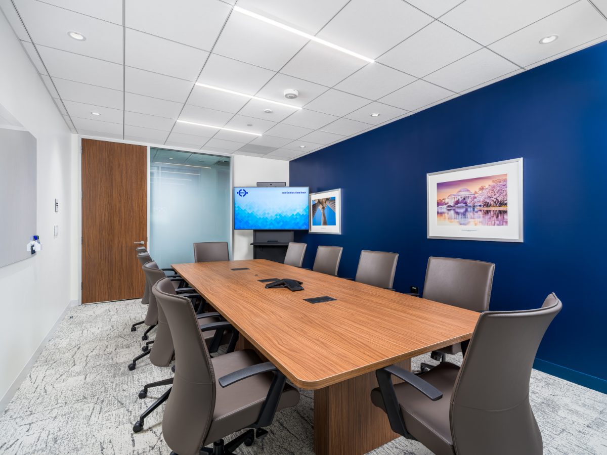 Interior conference room at JAMS Washington, D.C. — ten grey leather chairs, walnut table, cobalt wall with framed D.C. landmark prints, and a JAMS display.