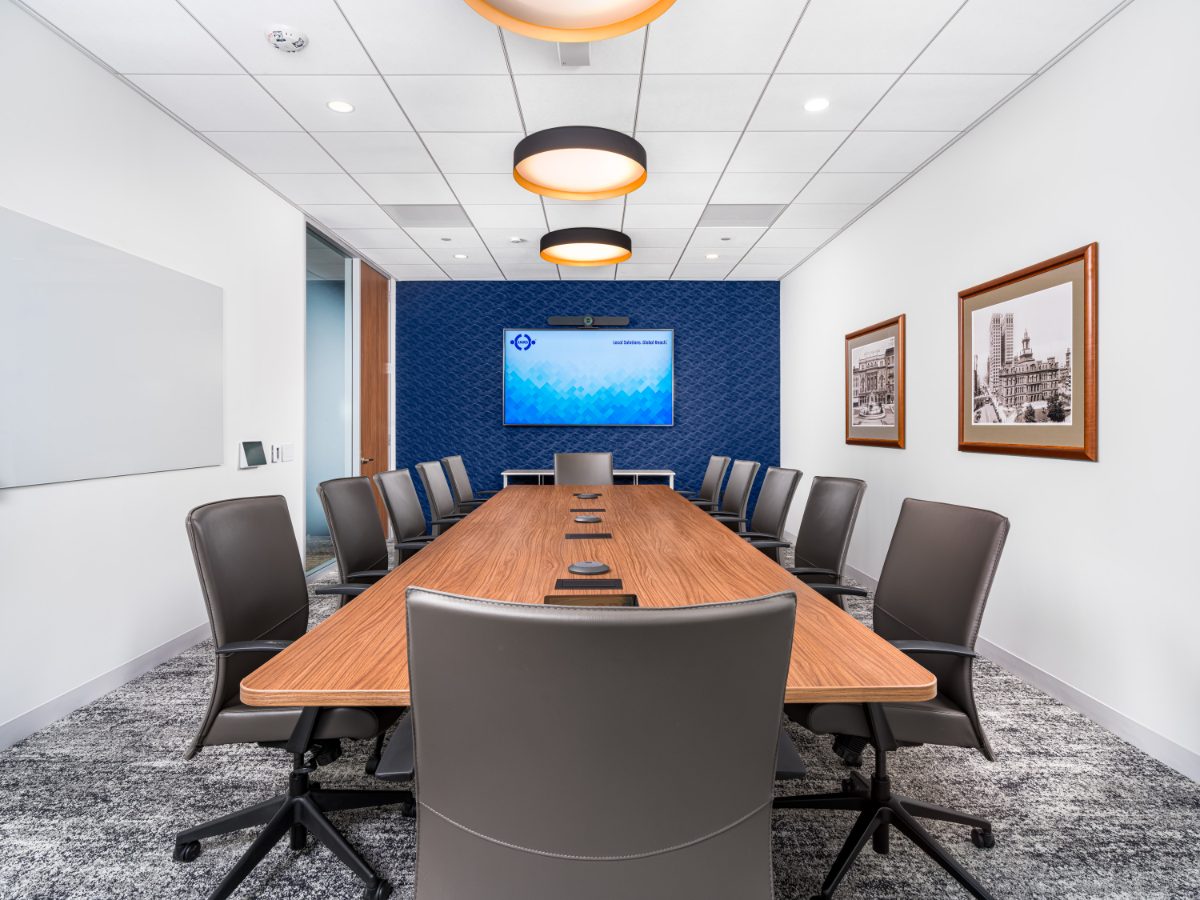 JAMS Detroit mid-size conference room — walnut table, fourteen grey leather chairs, drum pendants, JAMS display on cobalt back wall, and historic Detroit prints.