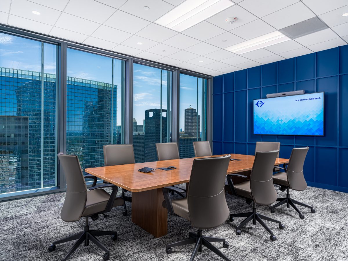 Eight-seat hearing room at JAMS Houston — walnut table, grey leather chairs, cobalt panel wall with JAMS display, and corner skyline windows.