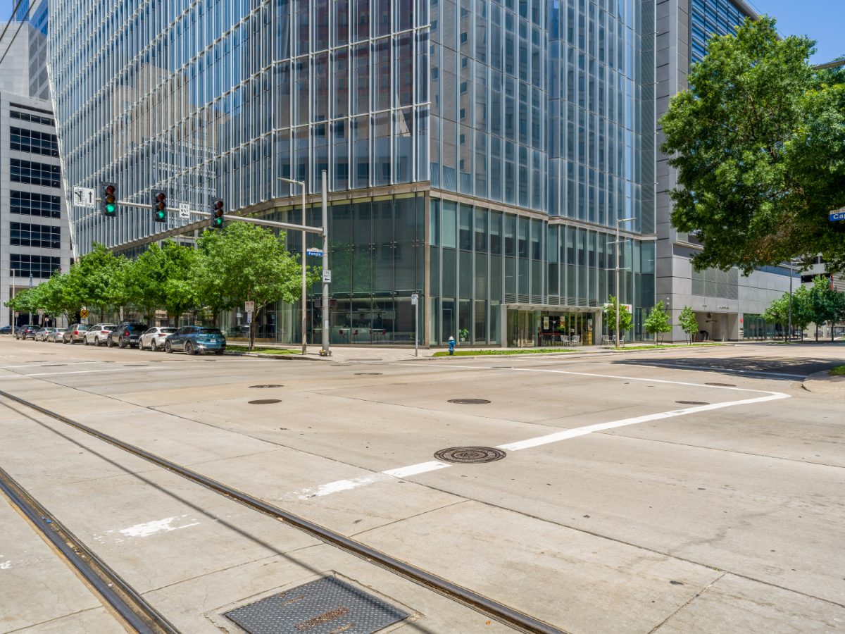 609 Main — modern glass tower housing JAMS Houston Resolution Center, photographed from across Fannin Street with METRORail tracks in the foreground.