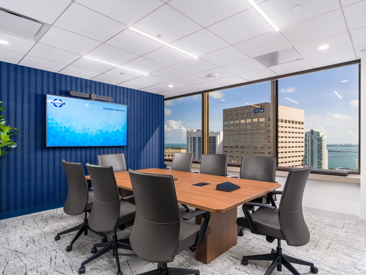 JAMS Miami Conference Room 14 on the 36th floor of One Biscayne Tower — walnut table, grey leather chairs, blue reeded acoustic wall, windows over downtown Miami.
