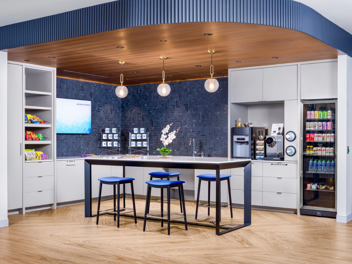 JAMS MN JAMS Café — symmetric curved walnut soffit ringed by cobalt fluted baffle, three glass-globe pendants, navy mosaic backsplash, cobalt bar stools.