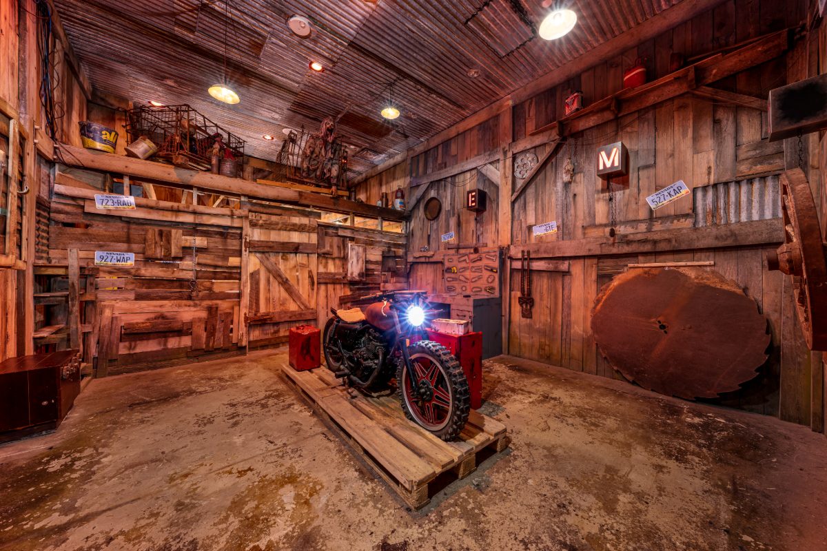 Interior of the Zombie Outbreak escape room at PanIQ Las Vegas, styled as a post-apocalyptic barn — weathered vertical wood plank walls, corrugated zinc ceiling, pendant industrial