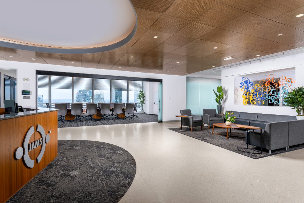 JAMS NY 34th-floor reception — walnut desk with JAMS emblem, oval wood atrium ceiling, conference room with skyline view, lounge with colorful art.