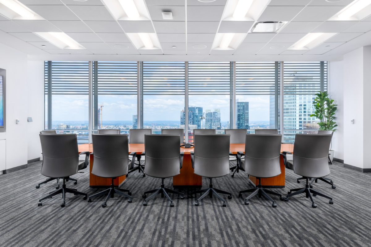 JAMS NY 34th-floor boardroom — 12-seat cherry table, grey leather chairs, floor-to-ceiling windows with NYT Building louvers framing the Manhattan skyline.