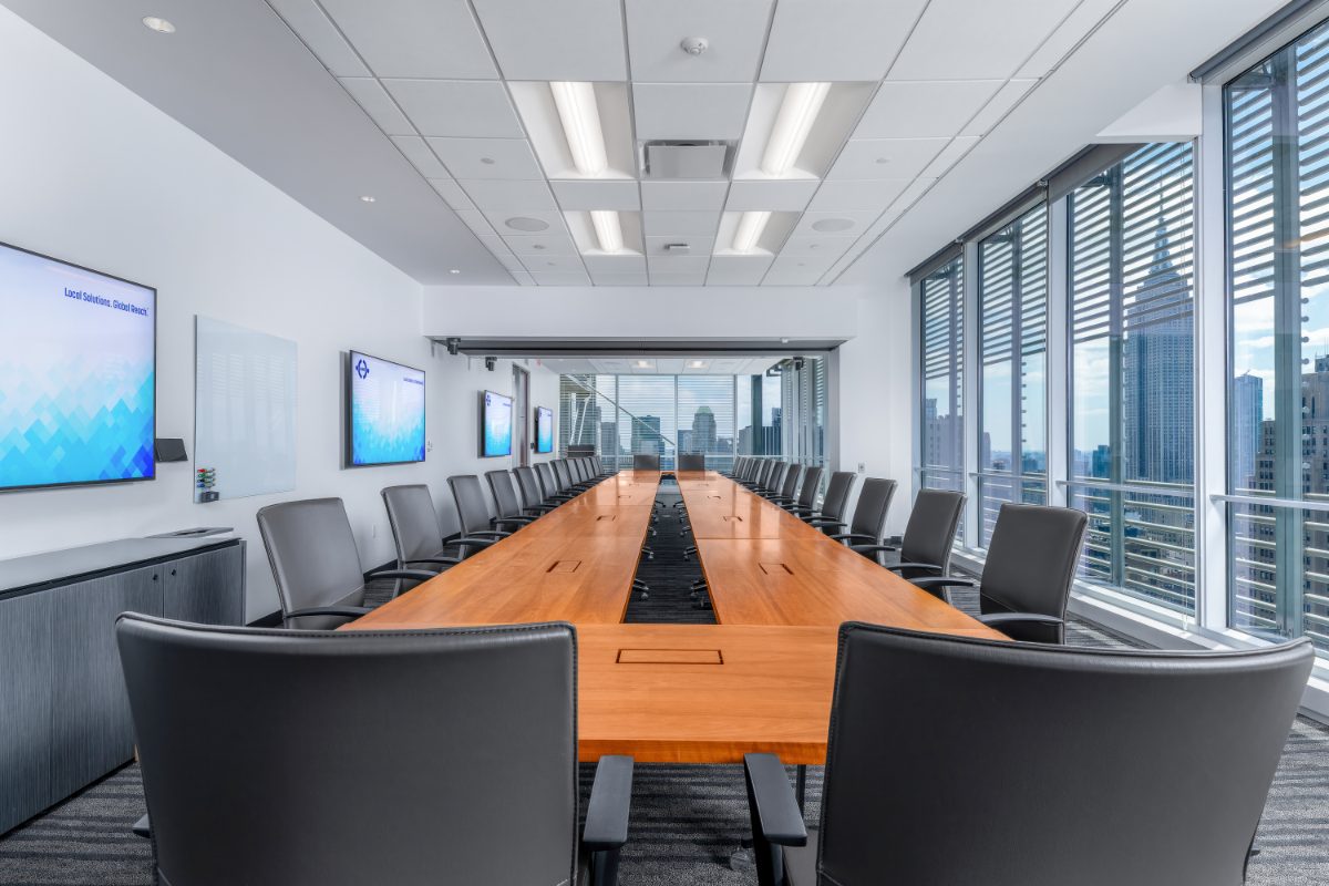 JAMS NY combined boardroom 26+28 — long cherry table seating ~30, multiple JAMS-branded displays, NYT louvers, Empire State visible through the windows.