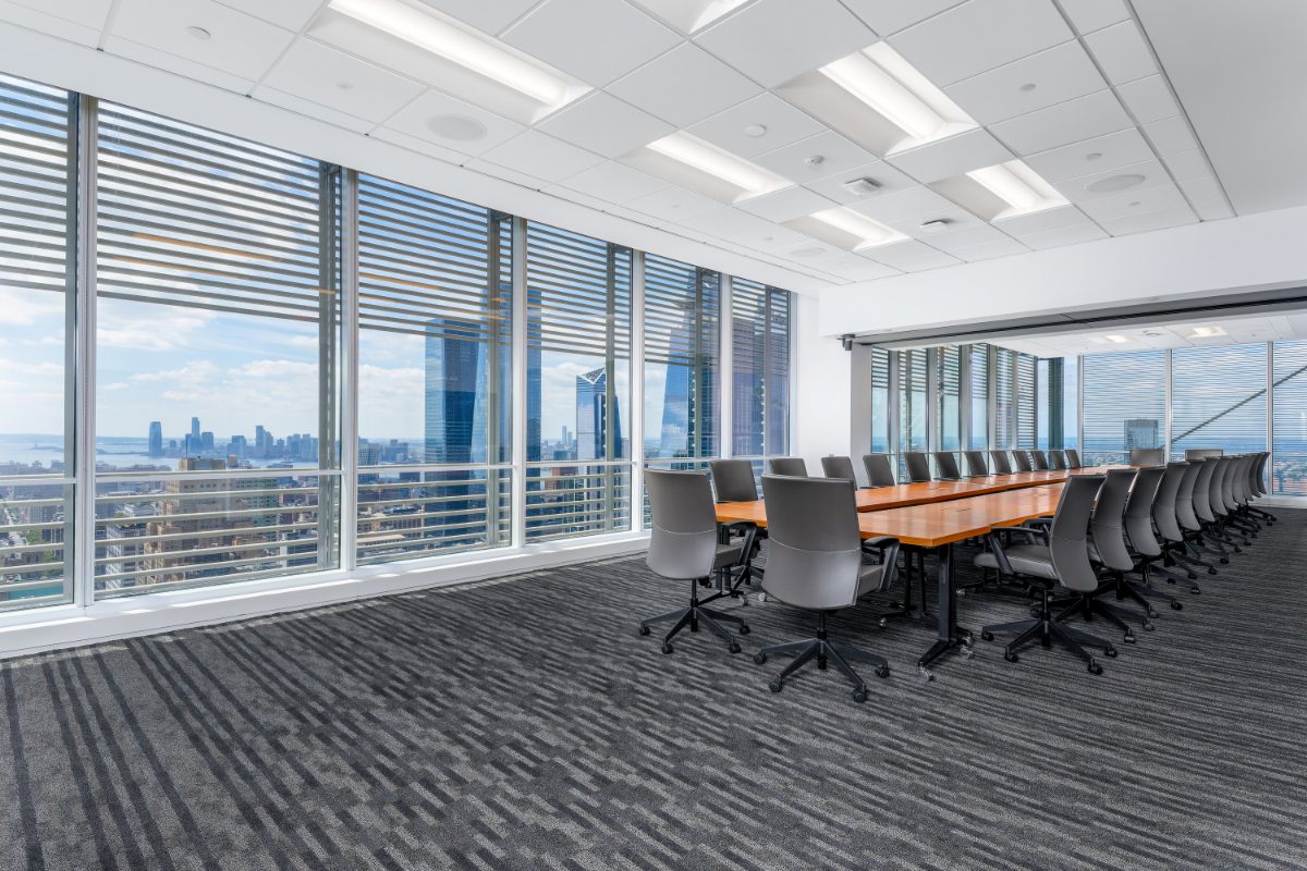 JAMS NY combined boardroom 26+28 — long cherry table, grey leather chairs, two walls of louvered windows onto Hudson Yards, Hudson River, and Jersey City.